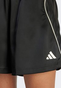 Sorte idrettsshorts laget av glatt stoff, med hvite detaljer langs kantene og en fremtredende hvit Adidas-logo nederst til venstre.