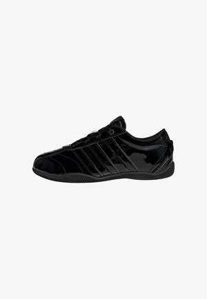 Sort blank lavt snøresneaker med tekstureret sål og diagonale stribedetaljer på siden, set fra ydersiden.