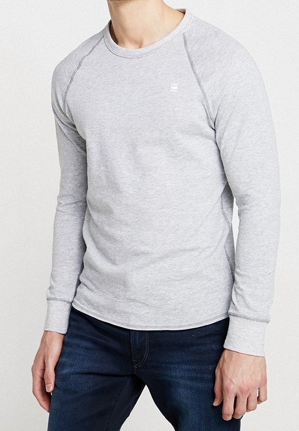 Chemise grise à manches longues avec un col rond et des coutures contrastées. Matière en coton douce, design ajusté, avec un petit logo sur la poitrine.