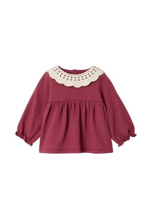 Langärmlige Babybluse in Mauve mit geraffter Taille und weißem Spitzenkragen mit Bogenkante auf einfarbigem Hintergrund.