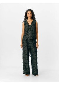 Ensemble composé d'un haut sans manches noir et d'un pantalon à jambes larges, présentant des motifs texturés et des bords effilochés, fabriqué en tissu léger.