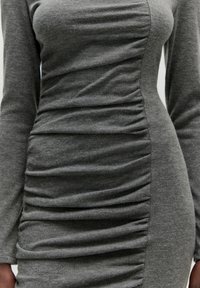 Graues Strickkleid mit langen Ärmeln, das seitliche Raffung für Textur und eine figurbetonende Passform bietet. Glattes Material.