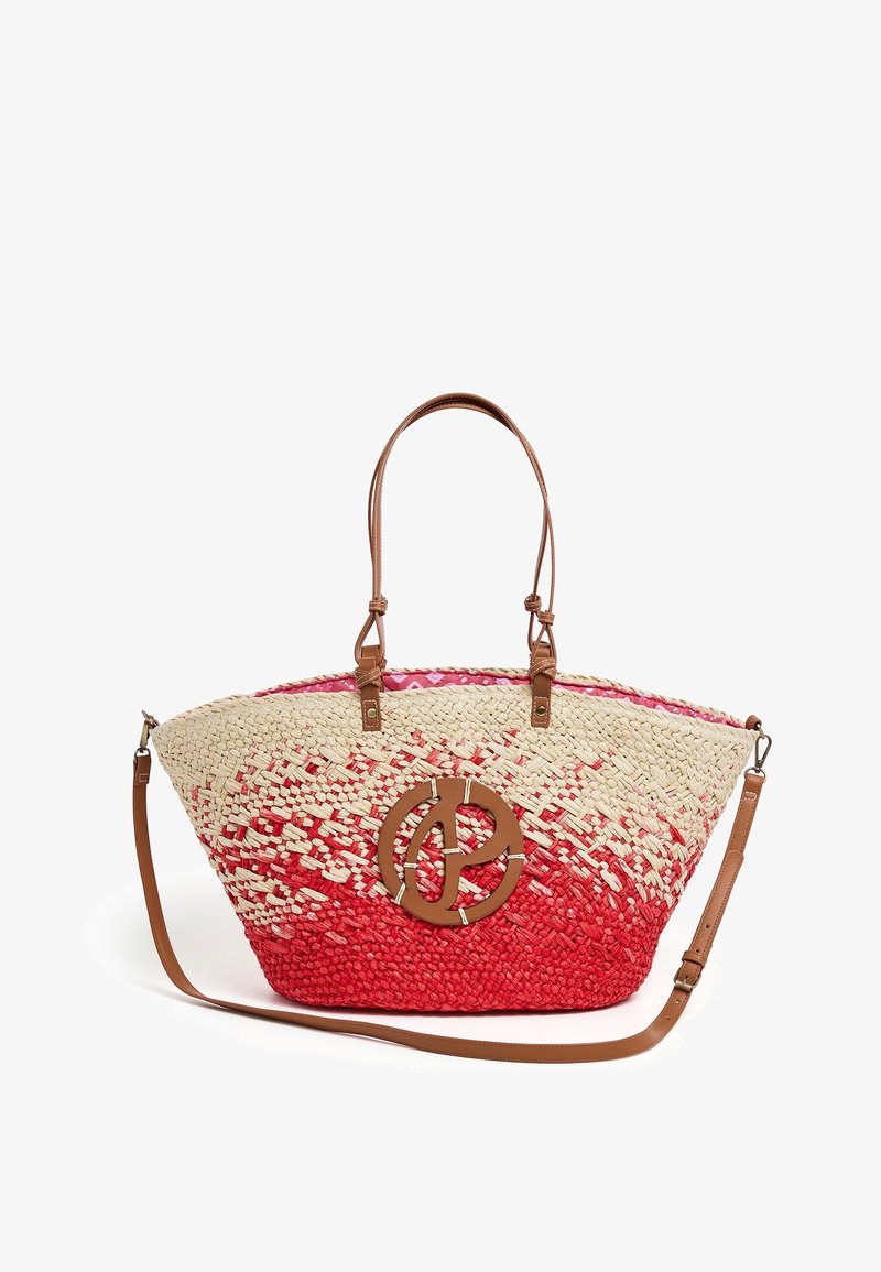 Sac fourre-tout en paille tissée avec un dégradé de couleur rouge et naturelle, deux poignées courtes, une longue bandoulière amovible en cuir marron, et un détail rond avec le logo marron.