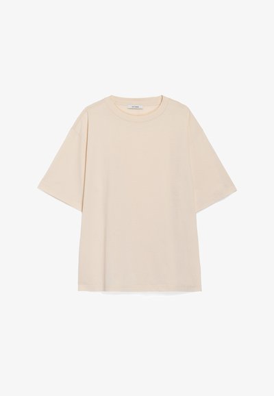 Světle béžové oversized tričko vyrobené z měkké bavlny, s kulatým výstřihem a krátkými rukávy, s jednoduchým designem bez viditelných vzorů.