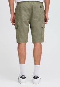 Pantalones cortos de carga verde hechos de algodón, con dos bolsillos laterales y dos traseros, con una cintura elástica y un corte relajado.