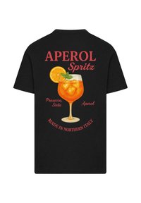 Black t-shirt featuring a colorful graphic of an Aperol Spritz cocktail with ice, an orange slice, and mint, along with text above and below.