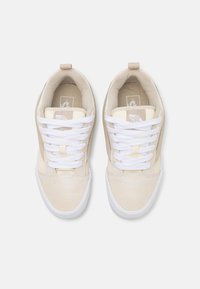 Beżowe sneakersy z białymi sznurówkami, gładkie i teksturowane materiały, zaokrąglony czubek i wysoka tylnia część. Posiadają małą pętelkę na pięcie.