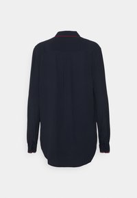 Navyblaues Langarmshirt mit Kragen, rotem Zickzackstich entlang des Halsausschnitts und geknöpften Manschetten. Glattes Material und leicht abgerundeter Saum.