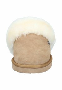 Beige suede slipper with fluffy cream faux fur trim. Rounded shape, flat sole, and a metal logo accent on the side. Soft texture.