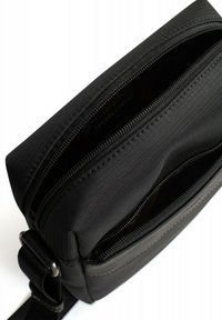 Borsa a tracolla nera con un esterno in tessuto texturizzato, duale scomparto con zip, tracolla regolabile e design elegante e minimalista.