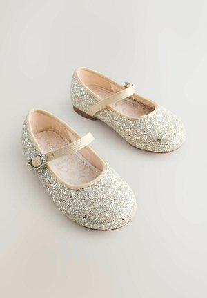 Lapsille tarkoitetut glitterillä päällystetyt vaaleat Mary Jane -kengät, joissa on pyöreä strassilukko remmissä ja pehmeät tyynylliset pohjalliset.