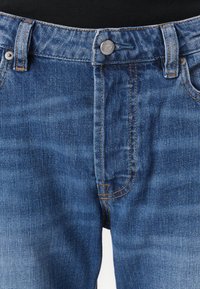 Blauwe denim jeans met een middelhoge taille, zilveren knoopsluiting en oranje stiksels. Beschikt over vijf zakken en een gladde textuur.