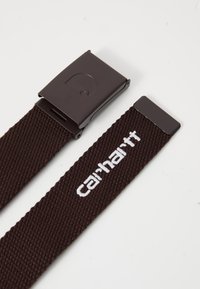 Bruine geweven stoffen riem met een donkerbruin metalen gesp met een logo en een witte logo-borduring op de band. Soepele textuur en duurzaam ontwerp.