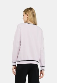 Maglione rosa chiaro con scollatura rotonda e bordi neri ai polsini e all'orlo. Vestibilità comoda con spalle cadute e texture a costine.