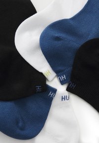 Set von Socken in Schwarz, Weiß und Blau. Hergestellt aus strukturiertem Material mit kontrastierenden Farbelementen und Logo-Detail an den Abschlüssen.