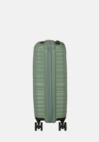Valigia rigida verde con texture a righe verticali, doppia cerniera e quattro ruote nere per una facile manovrabilità.