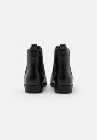 Svarta läderstövletter med slät yta, elastiska sidopaneler och dragflikar bak för enkel på- och avtagning. Låga blockklackar.