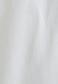 Tela blanca con una textura suave, que presenta sutiles pliegues. El color es uniforme, sin patrones ni acentos visibles.