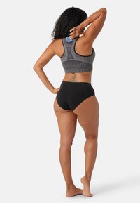 Svart högmidjad underkläder och en grå sport-bh med en strukturerad design, som har en racerback-cut och en blå accentdetalj på baksidan.