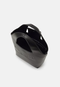 Sac fourre-tout en cuir noir avec des poignées découpées et un logo en relief "Steve Madden New York" sur le devant.