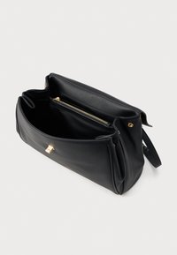 Czarna skórzana torebka o fakturowanej powierzchni, z kieszonką na zamek i złotymi elementami; otwiera się na przestronną wnętrze.