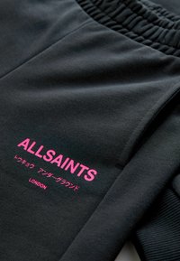 Čierna mikina so žebrovaným výstrihom, s jasne ružovým logom "ALLSAINTS" a japonským textom. Hladká textúra látky, ležérny dizajn.