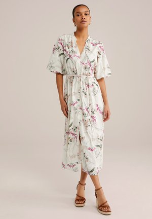 Floral midi dress in light fabric with a V-neck, elastic waistband, and short sleeves; features pink and green botanical prints and a side slit.