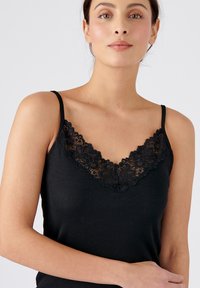Top de camisón negro con trimmings de encaje en el escote en V profundo. Presenta tirantes delgados ajustables y un tejido suave y elástico. Diseño simple y ajustado.