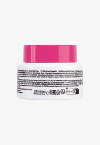 Hårmask i en rund, vit behållare med rosa lock. Innehåller 200 ml och har produktinformation på sidan på flera språk.