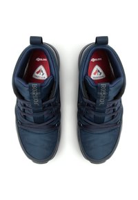 Zapatillas deportivas azul marino con un collar acolchado, detalles cosidos, cordones y suela de goma texturizada. Forro interior rojo con acentos del logo.
