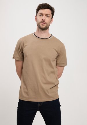 Beżowy T-shirt z bawełny z krótkimi rękawami i okrągłym dekoltem. Zawiera kontrastowy pasek wzdłuż kołnierza oraz subtelny detal z logo na rękawie.