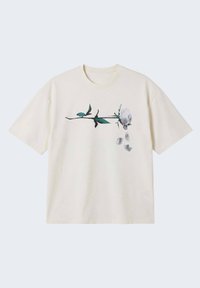 T-shirt à manches courtes de couleur crème avec un graphique horizontal de rose noire et verte et des pétales de rose grises tombantes au centre avant.