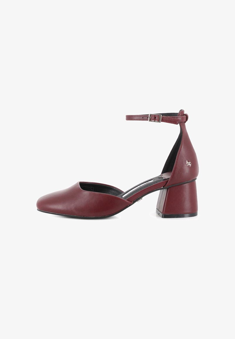 Zapato de tacón cuadrado para mujer en cuero burdeos con tira en el tobillo y hebilla plateada, punta afilada y laterales bajos.