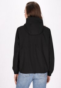 Jachetă neagră, ușoară, cu glugă, manșete elastice și hem cu șnur. Prezintă un design simplu și o textură de țesătură netedă.