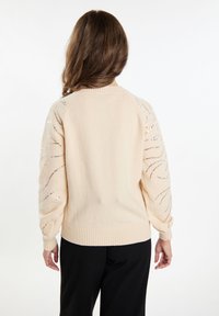Maglione beige chiaro con dettagli di paillettes sulle maniche, polsini e orlo a coste, e una vestibilità comoda. Morbido tessuto a maglia.