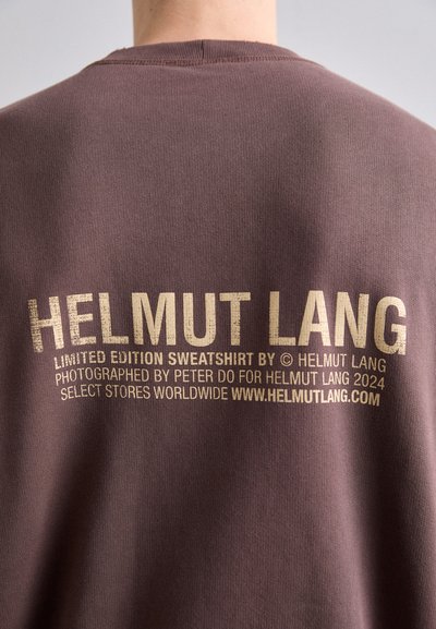 Sweatshirt castanho com texto em dourado, dizendo "HELMUT LANG", acompanhado de informações adicionais sobre edição limitada e detalhes de fotografia.