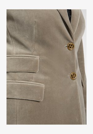 Beige corduroy blazer with two gold-tone buttons, notched lapels, and side pockets. Features a soft texture for a refined appearance.