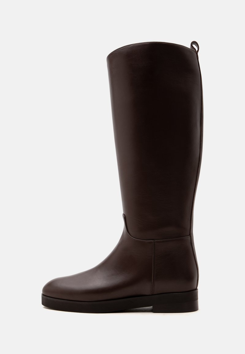 Botte haute en cuir brun foncé avec une semelle plate et une petite boucle à l'arrière du bord supérieur.