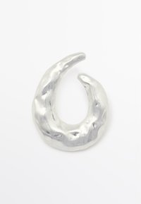 Zilverkleurige metalen oorbel in de vorm van een halve maan met een gestructureerd, onregelmatig oppervlak en een gepolijste afwerking. Geschikt voor verschillende stijlen.