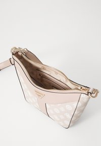 Sac à main rose à motifs avec quincaillerie dorée, fermeture éclair et bandoulière réglable. L'intérieur comprend plusieurs poches et un doublure à logo.