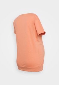 T-shirt de algodão pêssego com um corte descontraído, decote redondo e mangas curtas. Apresenta uma bainha reta e textura suave. Vista traseira exibida.
