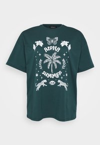 T-shirt in cotone verde dalla vestibilità ampia, con una grafica bianca che raffigura una palma, fiori, farfalle e leopardi che saltano.