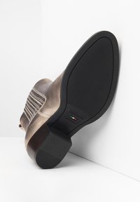 Bottine en bronze métallique avec cuir texturé, détail de couture verticale, semelle en caoutchouc et marque italienne sur le côté.