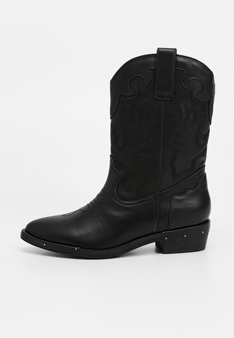 Bota de vaquero de cuero negro con diseño bordado, punta afilada, tacón bajo y apilado, y clavos decorativos en el tacón. Textura suave.