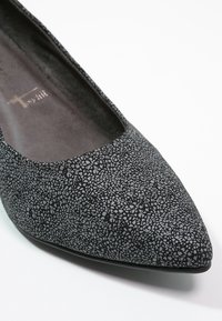 Chaussure plate à bout pointu texturée noire et grise avec doublure intérieure douce, vue en angle sur fond blanc.