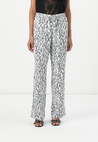 Pantaloni a gamba larga in bianco e nero con una cintura elastica e cordoncino. Tessuto leggero; le righe verticali creano un effetto fluttuante.