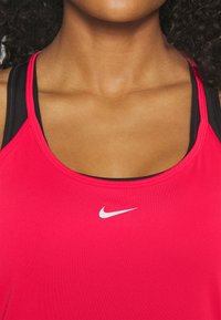 Canotta sportiva rosa brillante con scollo rotondo e spalline sottili, con uno strato inferiore nero e un logo Nike bianco sul davanti.