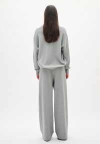 Sweatshirt en coton gris oversize avec une coupe relaxée et un pantalon large assorti, présentant une texture douce et des détails de couture subtils.