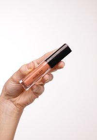 Lucidalabbra in un tubo trasparente con un coperchio nero, che mostra un colore pesca nude. Il marchio "INGLOT" è stampato sul lato.