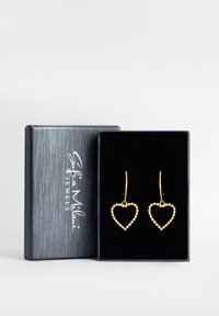 Gul hjärtformade örhängen med pärldetaljer, hängande på smala krokar, presenterade i en svart sammetfodrad låda med silverbranding.
